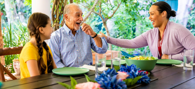 three people sitting at outdoor table laughing together