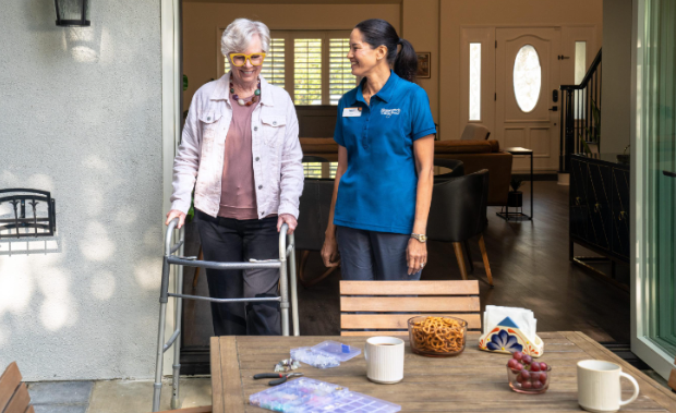 woman smiling and walking with cane with nurse beside her